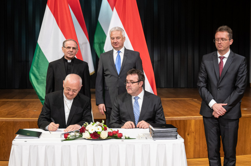 Ternyák Csaba egri érsek és Palkovics László innovációs és technológiai miniszter aláírja a dokumentumot. Mögöttük Semjén Zsolt miniszterelnök-helyettes és Dolhai Lajos, az  Egri Hittudományi Főiskola rektora.
